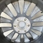 Close-up of a car alloy wheel with adhesive balancing weights attached around the rim for balancing purposes.