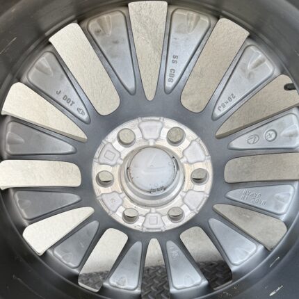 Close-up of a car alloy wheel with adhesive balancing weights attached around the rim for balancing purposes.