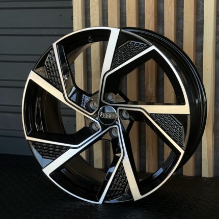 Audi alloy wheel with a bold black and silver five-spoke design and a visible center hub featuring the Audi logo.