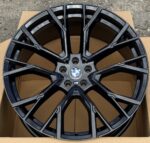 Black BMW alloy wheel with an eight-spoke design resting in a cardboard box.