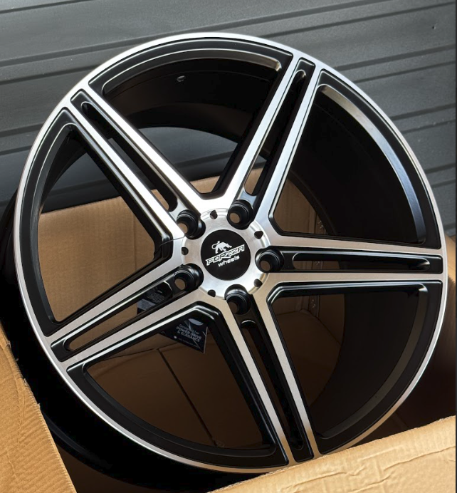 DSK-R22-5x112-f87cc5_0-1 Black and silver five-spoke alloy car wheel in an open cardboard box, showing a machined finish and center cap.